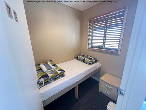 a small bedroom with a bed and a window at Stay Hostel Rotorua in Rotorua