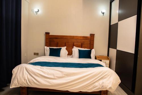 1 dormitorio con 1 cama grande con almohadas azules en C&C Apartment at Kileleshwa en Nairobi