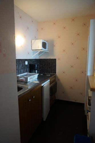 - une cuisine avec un évier et un four micro-ondes sur le mur dans l'établissement Résidence Roches Rousses A - 2 pièces 6 personnes MAE-2826, à Orcières