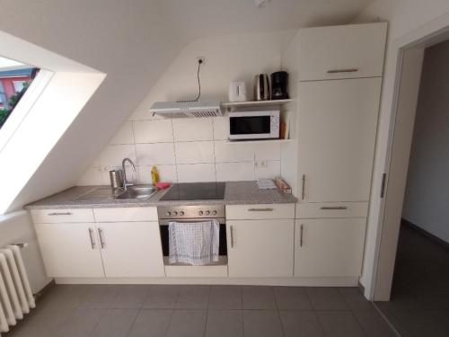 a white kitchen with a sink and a microwave at Hotel Victoria in Weil am Rhein