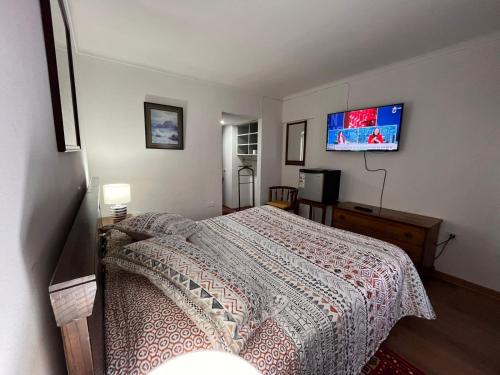 a bedroom with a bed and a flat screen tv at NEW HOTEL CRUZ DEL SUR in Concepción