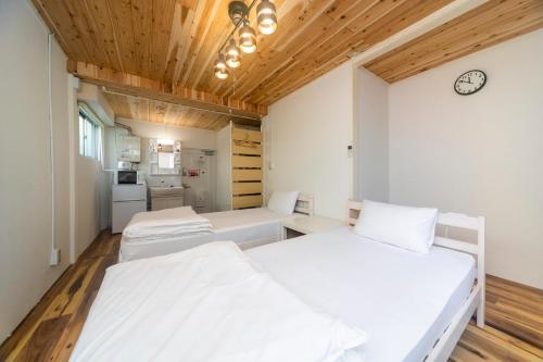 - 2 lits dans une chambre dotée de plafonds en bois dans l'établissement コインズホステル天神ペット宿泊可, à Fukuoka
