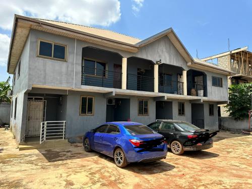 due auto parcheggiate di fronte a una casa di Chila Apartment a Accra