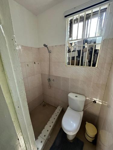 e bagno con servizi igienici, doccia e finestra. di Chila Apartment a Accra