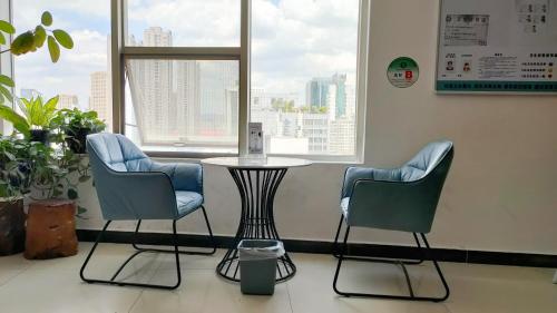 2 sillas y una mesa en una habitación con ventana en Ha Luo Hotel en Kunming