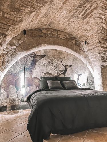 1 dormitorio con 1 cama grande en una pared de piedra en Le Pandore, en Junas