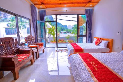 - une chambre avec 2 lits, des chaises et une grande fenêtre dans l'établissement Trang An Nature View Homestay, à Nguyên Ngoại