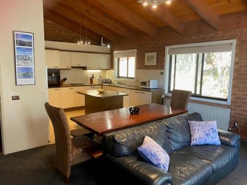 uma sala de estar com um sofá de couro e uma mesa de madeira em LimLimBu 12 em Falls Creek