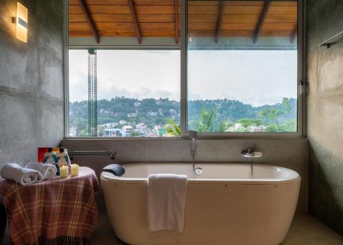 a bath tub in a bathroom with a large window at Kandy Tree Tops in Kandy