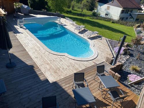 une vue aérienne d'une piscine sur une terrasse en bois dans l'établissement Le Chalet de la Devinière, bain nordique extérieur chauffé, à Xonrupt-Longemer