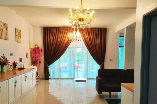 a living room with a chandelier and a large window at Homestay Kampar Putra in Kampar