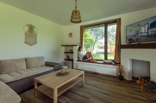 a living room with a woman sitting on a window sill at Ciucea185 -Casa din Livadă in Ciucea