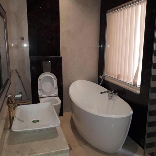 La salle de bains est pourvue d'une baignoire blanche et de toilettes. dans l'établissement Blue Revan chalet, à Salalah