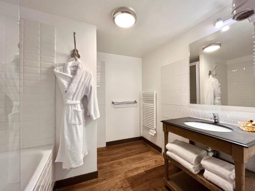 a white bathroom with a sink and a bath tub at Hôtel des Basses Pyrénées - Bayonne in Bayonne