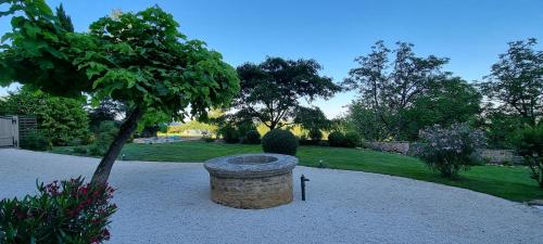 a stone fountain in a park with a tree at Le Clos de la Tour in Sainte-Nathalène