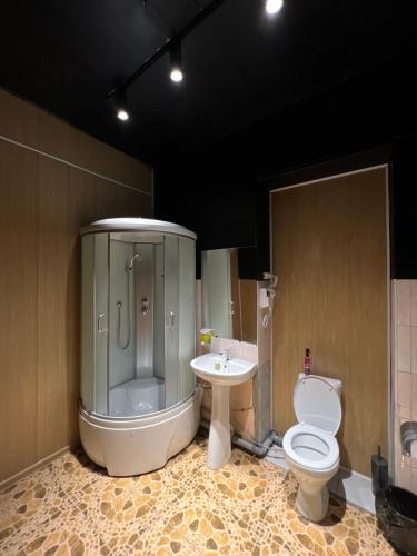 een badkamer met een douche, een toilet en een wastafel bij Capsule Hostel in Karakol