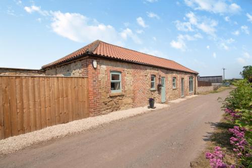 The Old Moat Barn - With Private Hot Tub في ستوكتون-أون-تيز: مبنى من الطوب مع سياج وطريق ترابي