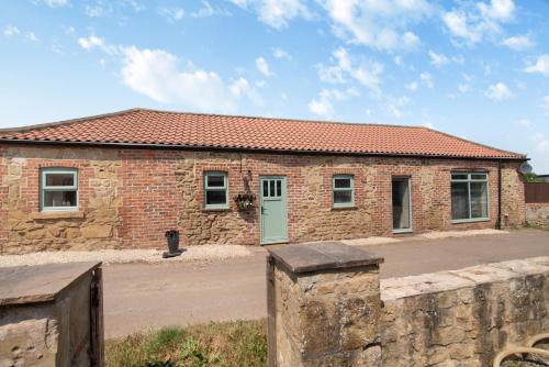a brick building with a green door and a fence at The Old Moat Barn - With Private Hot Tub in Stockton-on-Tees