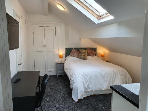 a bedroom with a bed and a desk and a window at Lyndene House in Huddersfield