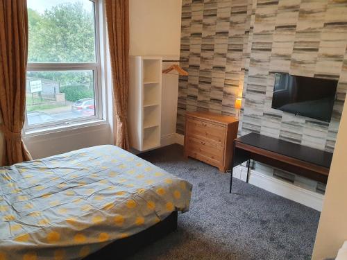 a bedroom with a bed and a desk and a television at Lyndene House in Huddersfield