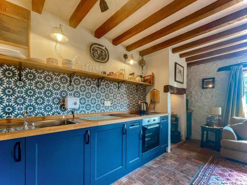 cocina con armarios azules y encimera en Stable Cottage, en Leintwardine