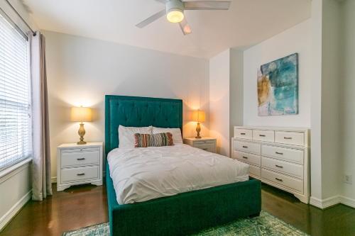 ein Schlafzimmer mit einem Bett mit einem grünen Kopfteil und zwei Nachttischen in der Unterkunft Montrose Lodge by Dunyha in Houston