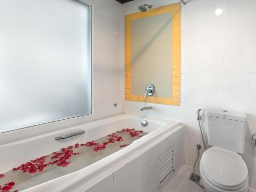 a bathroom with a bath tub with red flowers on it at Cocoon APK Resort & Spa in Patong Beach