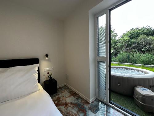 1 dormitorio con bañera, cama y ventana en GRAND HYATT APPARTMENTS, en Podhájska