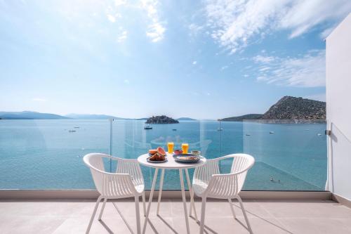 a table with food and drinks on a balcony with a view of the ocean at Nelly's Apartments in Tolo