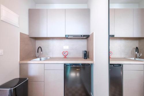 a small kitchen with white cabinets and a dishwasher at Nelly's Apartments in Tolo