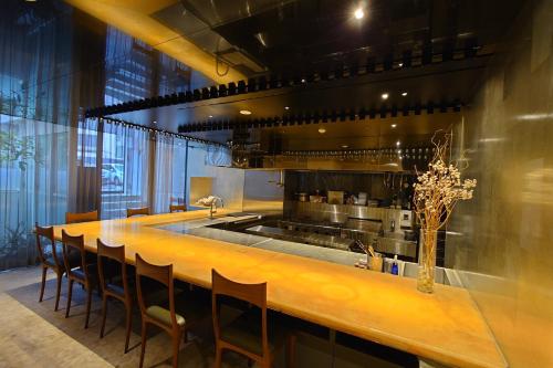 a large kitchen with a long wooden bar with chairs at A10 hotel azabu ten in Tokyo