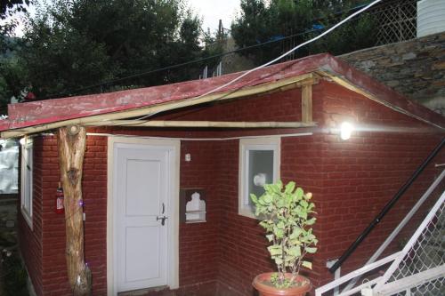 a small red brick house with a white door at Infinity Hill Village Mukteshwar in Mukteswar