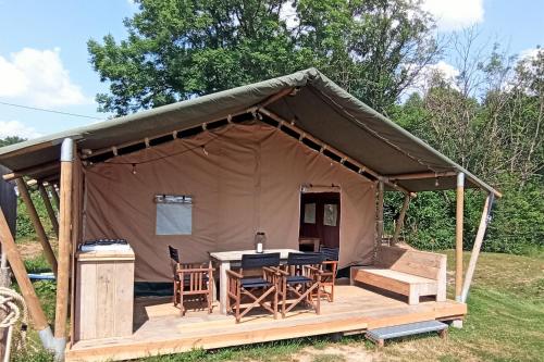 Zelt mit Tisch und Stühlen auf einem Feld in der Unterkunft Le Lodge de la Chouette in Quarré-les-Tombes