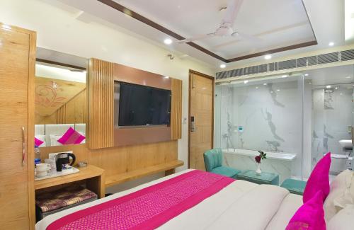 a bedroom with a bed and a tv and a tub at Aman International-A New Unit of Aman Continental in New Delhi