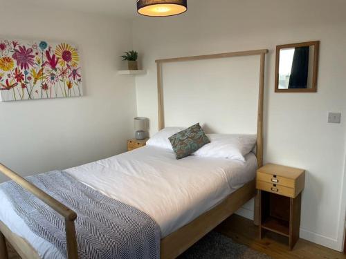 a small bedroom with a bed with a nightstand and a picture at Stunning, Modern and Spacious House - Truro in Truro