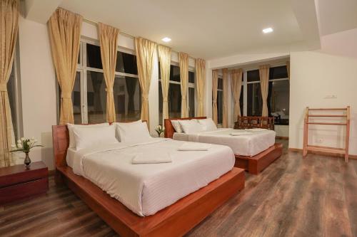 a bedroom with two beds and windows at Richfields in Ooty