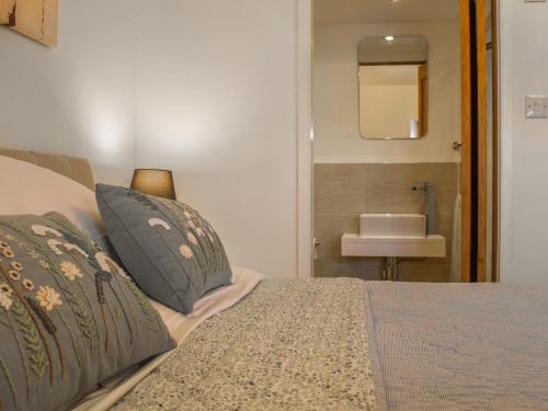 a bedroom with a bed and a bathroom with a sink at Chapel House in Bourton on the Water