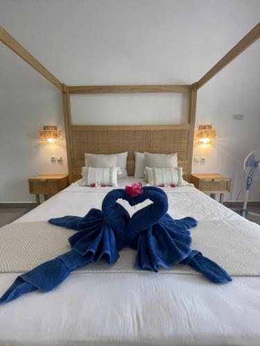 a bed with two blue towels in the shape of a heart at Blue EmOcean resort in Moyo Island