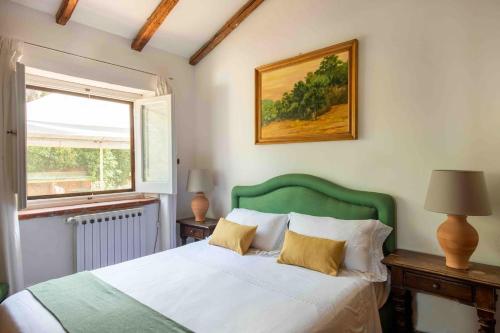 a bedroom with a bed with a green headboard and a window at Villa Grimodi in Caronia Marina