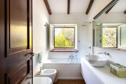 a bathroom with a white tub and a sink and a mirror at Villa Grimodi in Caronia Marina