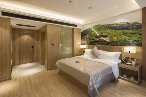長沙市にあるMorning Hotel, Changsha Provincial Government Metro Stationのベッドルーム1室(ベッド1台付)が備わります。壁には絵画が飾られています。