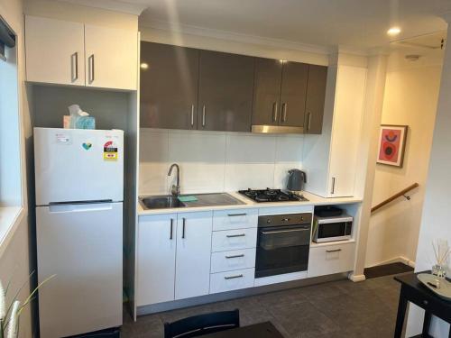 a kitchen with white cabinets and a white refrigerator at Adorable 1 bedroom Unit in Coombs in Weston Creek