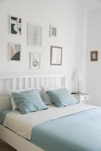 a white bedroom with a bed with blue pillows at Rachel suite by the pool Paphos in Paphos City