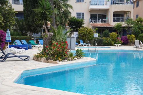 a swimming pool in a hotel with chairs and flowers at Rachel suite by the pool Paphos in Paphos City