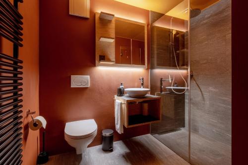 a bathroom with a toilet and a sink and a shower at Belmont- Apartment Haus in Arosa