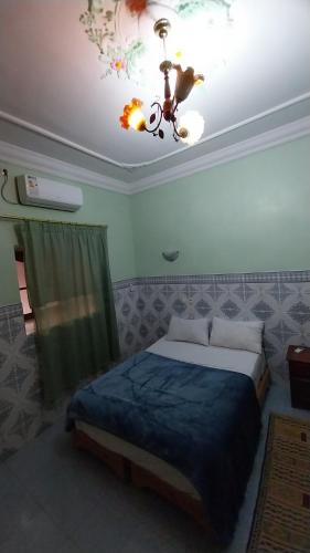 a bedroom with a bed and a ceiling with a chandelier at Maroc Galacx in Ouarzazate