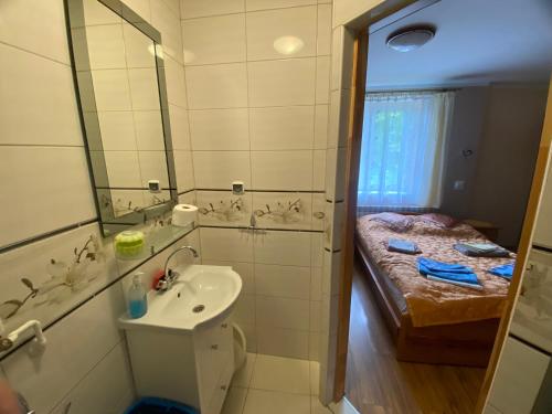 a small bathroom with a sink and a bed at Wynajem Pokoi gościnnych Jaś i Małgosia in Zakopane