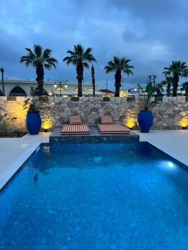 a swimming pool with palm trees and a stone wall at Cora May Central Villa with private pool 200m to the beach in Faliraki