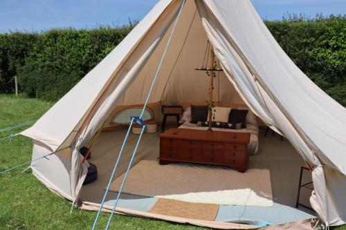 a canvas tent with a bed in a field at Rescorla Retreats- Poldark in Mevagissey