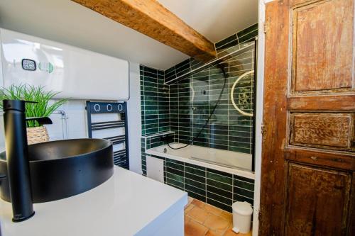 La salle de bains est pourvue de murs carrelés verts et d'un lavabo. dans l'établissement Charmant T2 au Cœur d'Ajaccio - Parking & AC, à Ajaccio